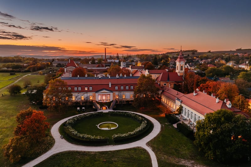 Letecký pohľad z dronu na hotel Chateau Béla so záhradou a parkom v podvečer.